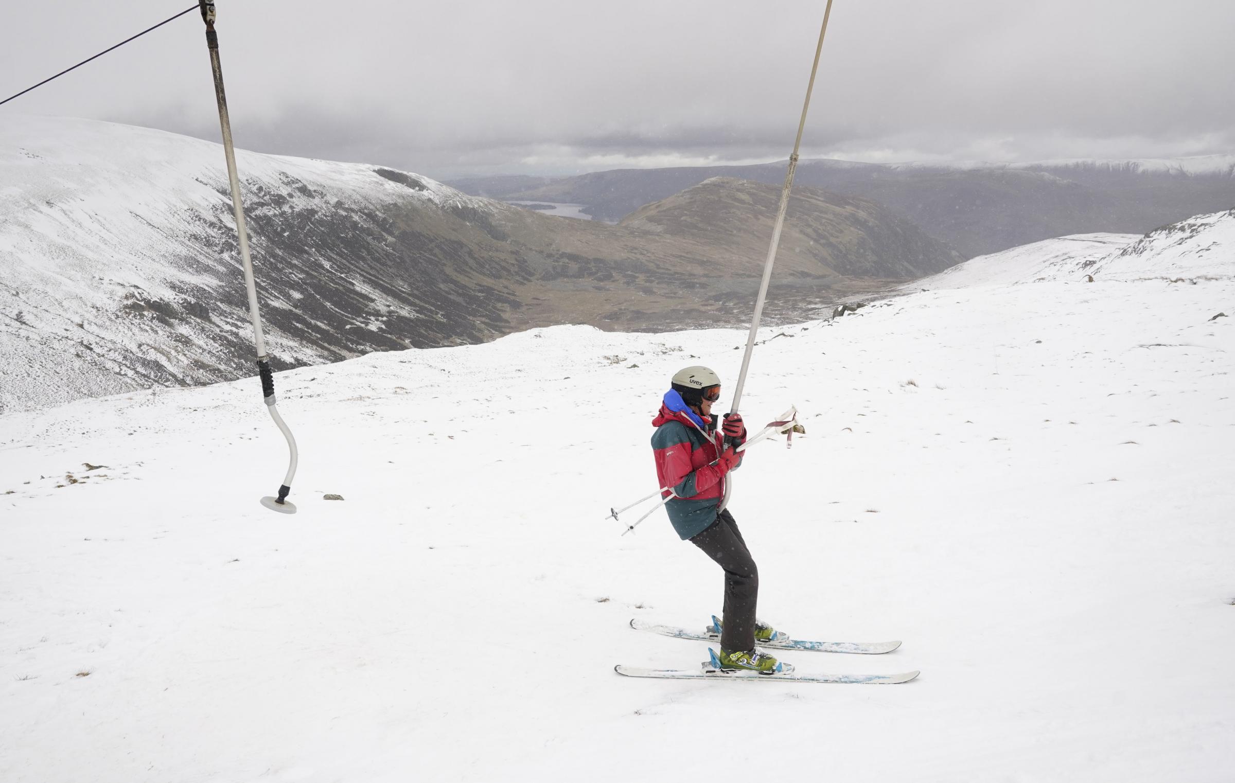 A skier uses a button lift to ascend at the Lake District Ski Club on Raise, next to Helvellyn in the Lake District National Park, with Ullswater behind, after an unseasonal May snowfall allowed the reopening of the slopes. Picture date: Thursday May 6,