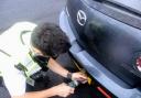 Stock image of police fitting anti-theft screws to number plates