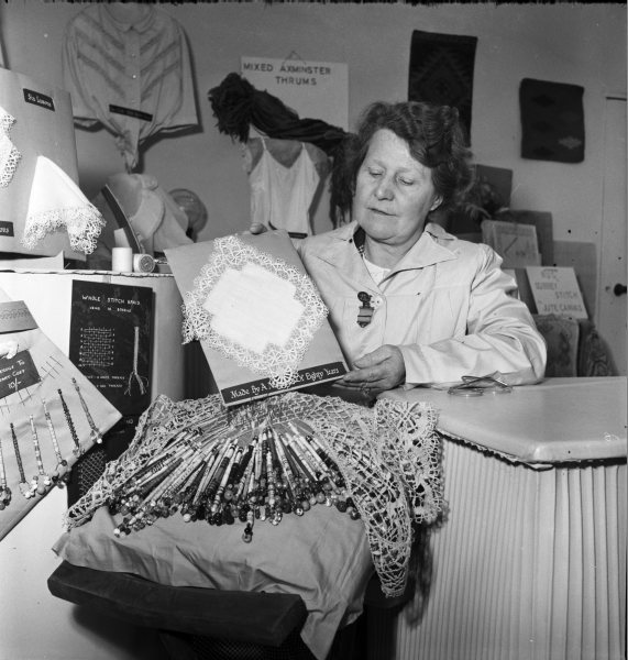 A woman displaying an example of lace-making on a stand promoting the craft