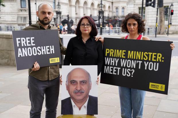 (Left to right) Aryan Ashoori, Sherry Izadi and Elika Ashoori, the son, wife and daughter of Anoosheh Ashoori, a British man who has been jailed in Iran, stage an ’empty chair’ protest opposite Downing Street