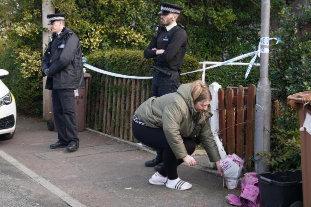 TRIBUTES: A woman lays flowers at a house in St Helens after a 17-month-old girl died after being attacked by a dog. Picture: PA Wire