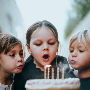 Healthy eating policy leaves kids blowing out candles on wooden birthday cake