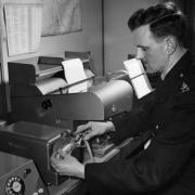 Officer in the information room prepares a teleprinter message for distribution c.1950s 